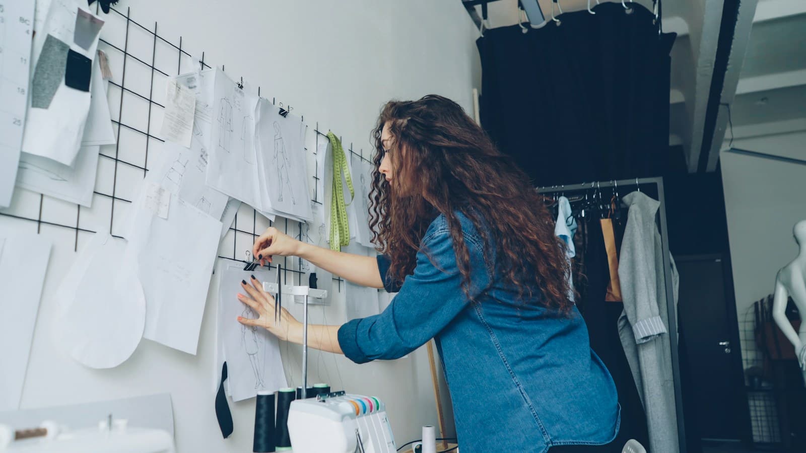 Designer de moda trabalhando diante de desenhos e referências