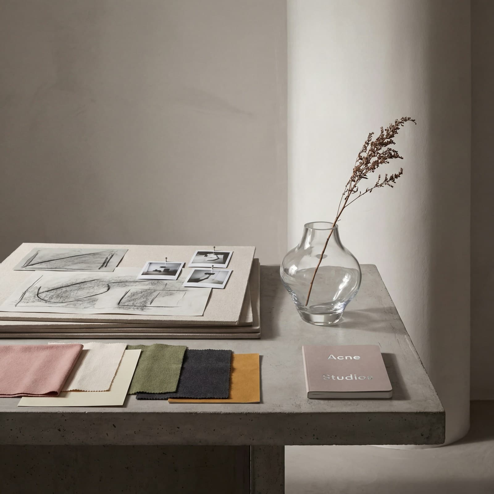 Amostras de tecido, desenhos e fotografias sobre uma mesa de projeto